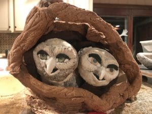 Two owl sculptures nestled in a nest.